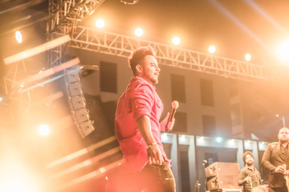 A singer in red on a stage strung with amber lights