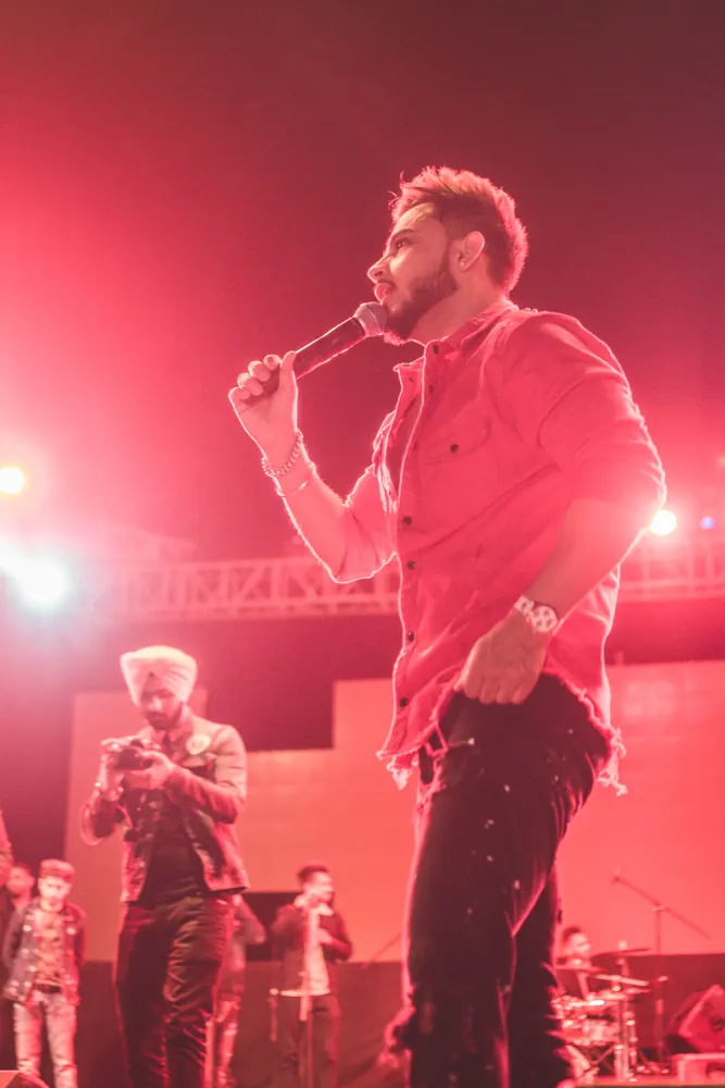 A singer in a red shirt, mid-song, under pink light