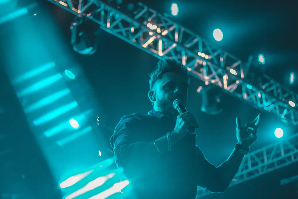 A singer under the lighting truss, in teal light