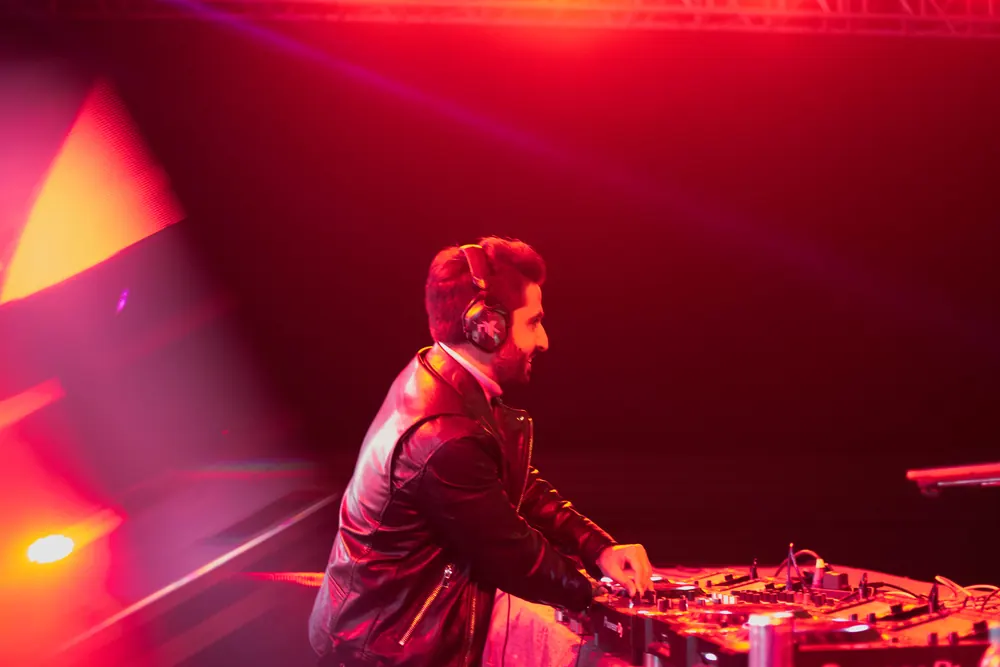 A DJ in a leather jacket at the decks, in red light