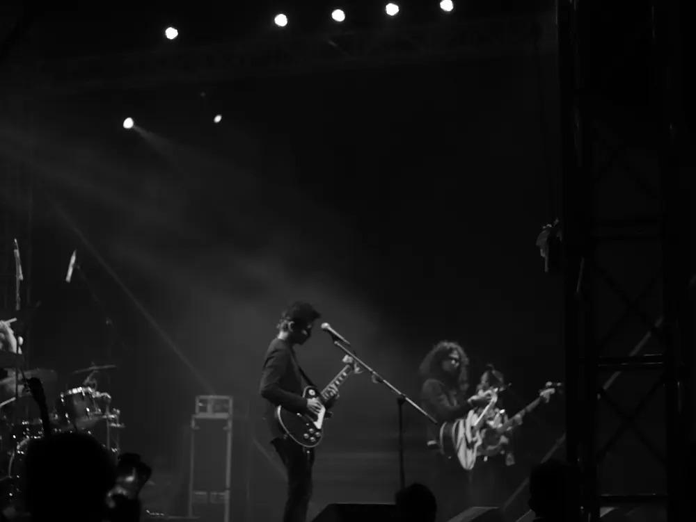 The band on a dark stage under a row of lights, in black and white