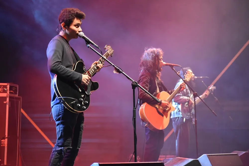 Three musicians on stage in purple light