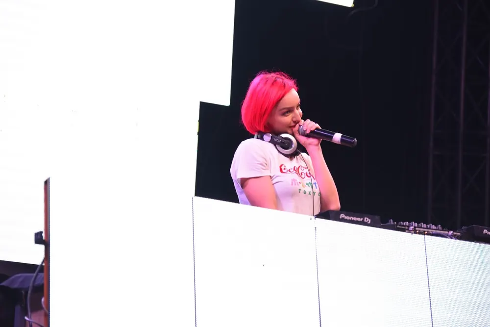 A DJ with red hair on the microphone at the decks