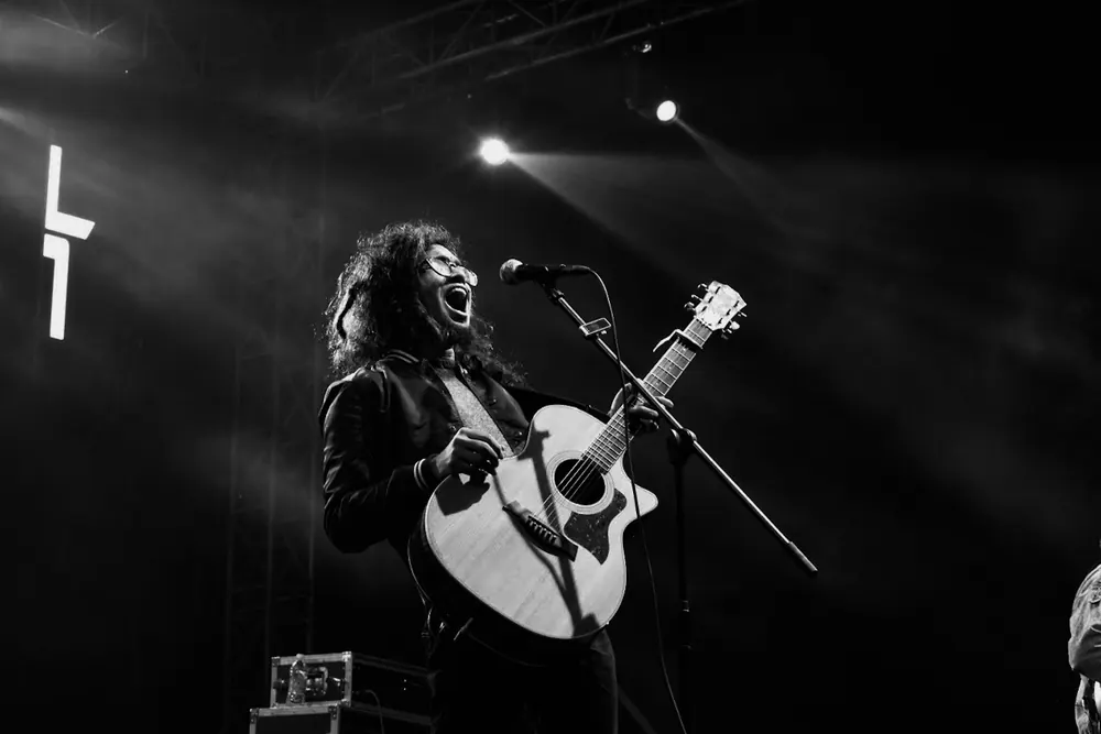 A guitarist singing with his head back, in black and white