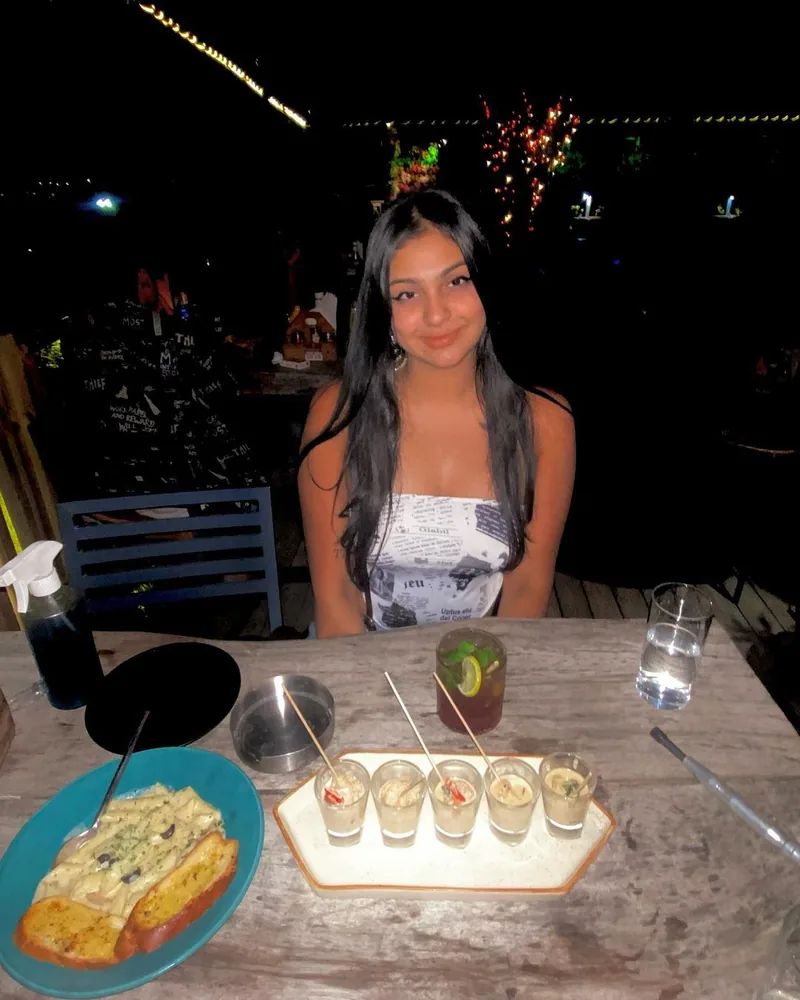 A creator at a table at night, with food and shots